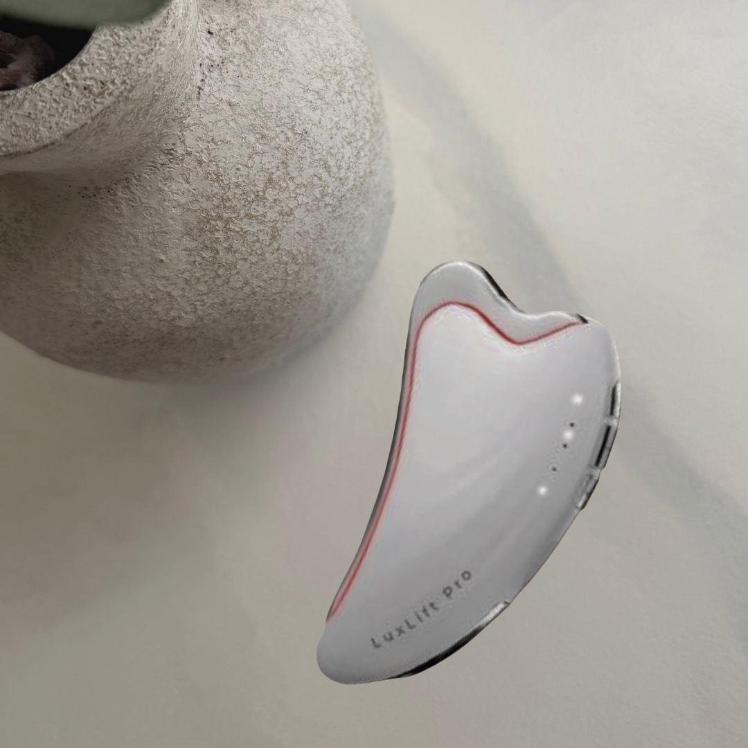 Gua Sha tool on a white surface with a plant in the background